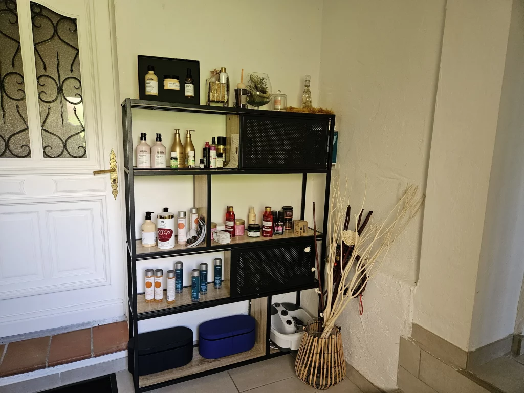 Étagère avec des produits de beauté et soins capillaires assortis, à côté d'un bouquet de branches décoratives.